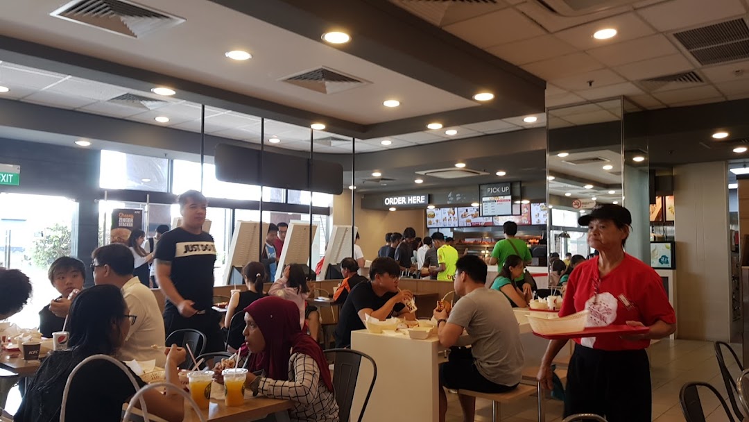 A bustling KFC restaurant interior with customers dining and staff serving food.