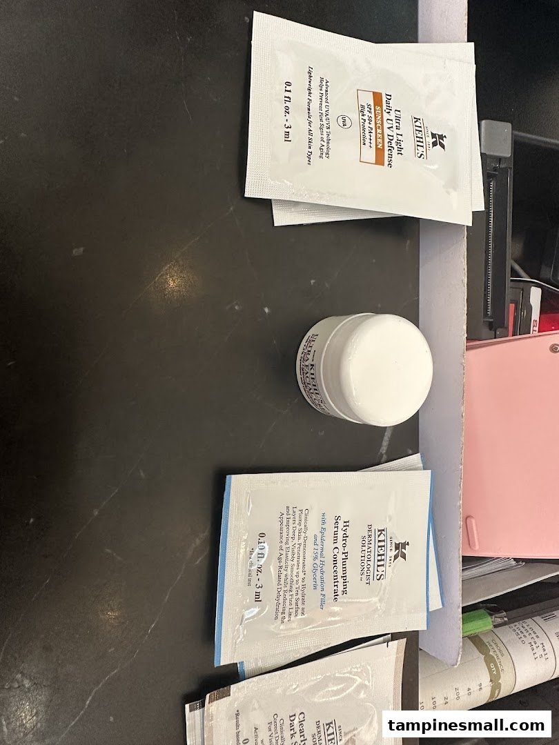 Kiehl's skincare samples and a product jar displayed on a dark counter.