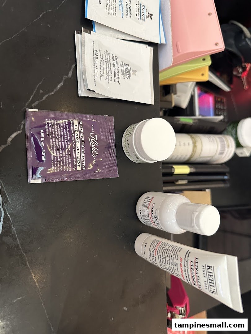 Various Kiehl's skincare products and samples, including cleansers and treatments, displayed on a dark surface.