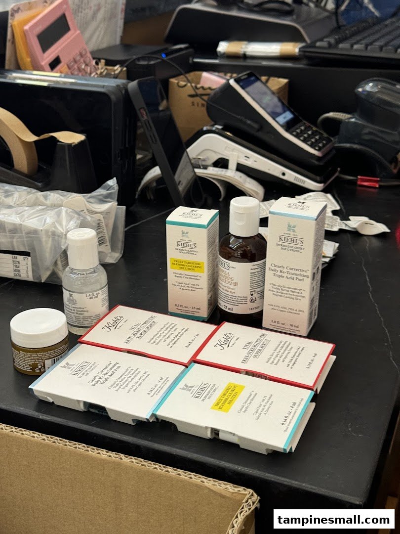 Kiehl's skincare products, including serums and peels, displayed on a counter with payment terminals.
