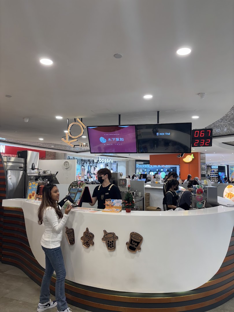 A customer orders at the bustling KOI Thé counter, showcasing the shop's vibrant atmosphere.