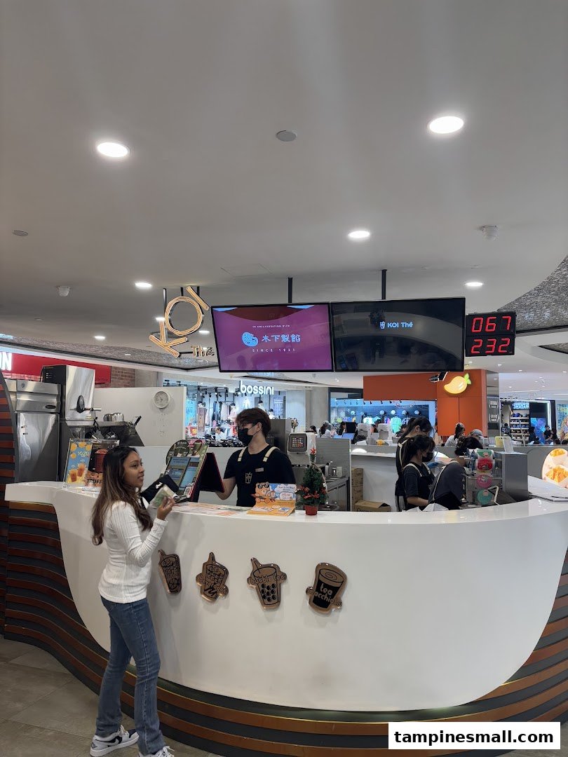A customer orders at the bustling KOI Thé counter, showcasing the shop's vibrant atmosphere.