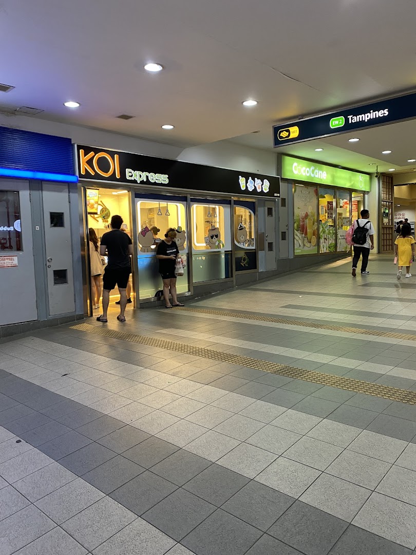 The brightly lit KOI Express shop front with customers waiting, located in Tampines Mall.