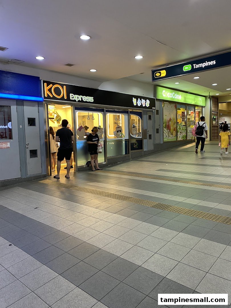 The brightly lit KOI Express shop front with customers waiting, located in Tampines Mall.