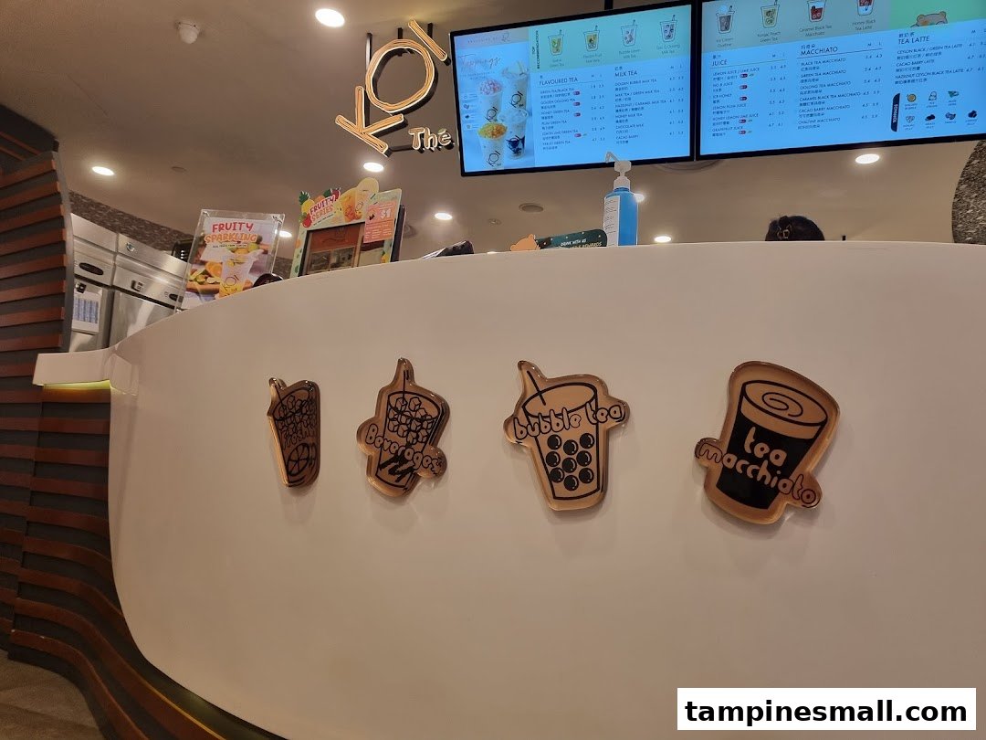 A bright interior shot of KOI Thé's counter with digital menu boards displaying various bubble tea options.
