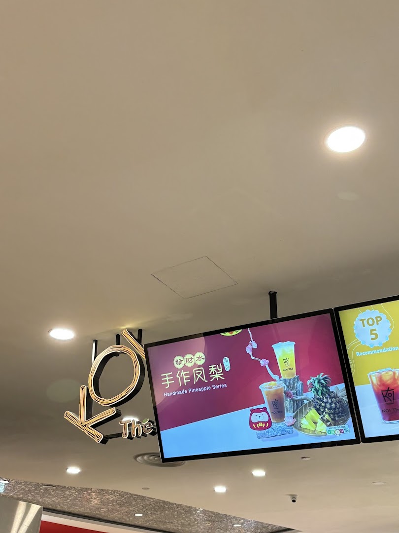 Close-up of KOI Thé's illuminated signage and digital display promoting their Handmade Pineapple Series.