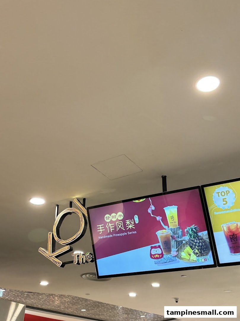 Close-up of KOI Thé's illuminated signage and digital display promoting their Handmade Pineapple Series.