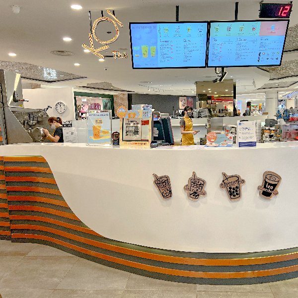 Interior view of KOI Thé with staff preparing drinks and digital menus displayed above the counter.