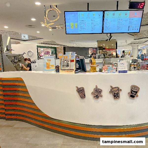 Interior view of KOI Thé with staff preparing drinks and digital menus displayed above the counter.