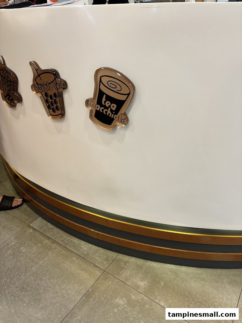Close-up of KOI Thé counter featuring decorative icons for bubble tea and tea macchiato.