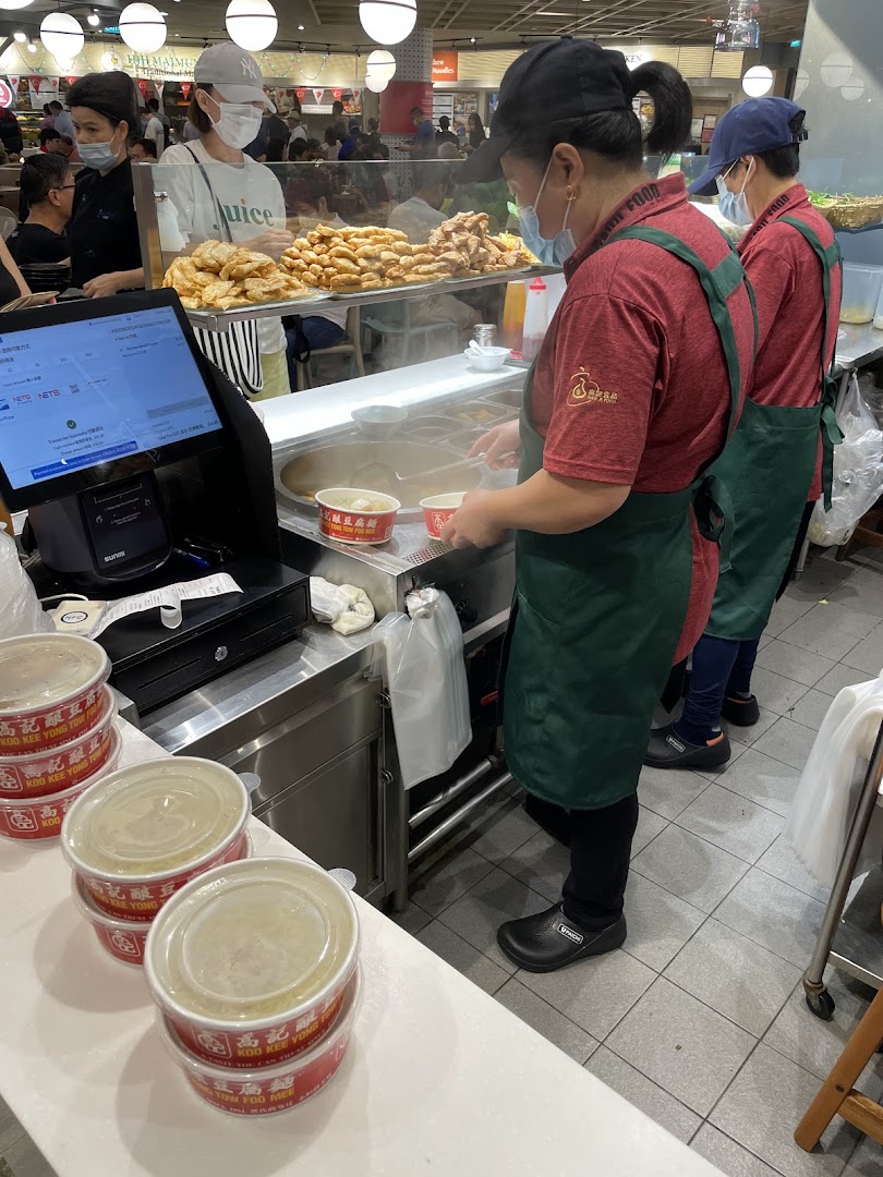 Staff at Koo Kee Yong Tow Foo Mee prepare fresh Yong Tow Foo dishes for customers in a bustling food court setting.
