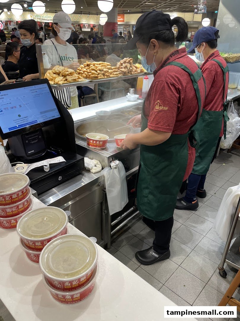 Staff at Koo Kee Yong Tow Foo Mee prepare fresh Yong Tow Foo dishes for customers in a bustling food court setting.