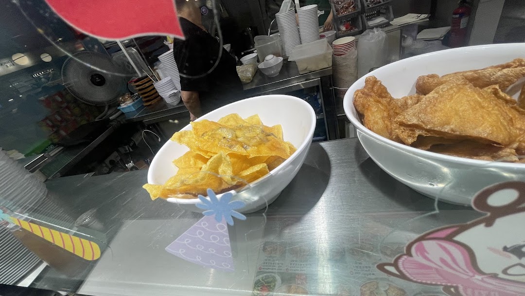 Bowls of crispy fried wontons and beancurd skin displayed at a food stall.