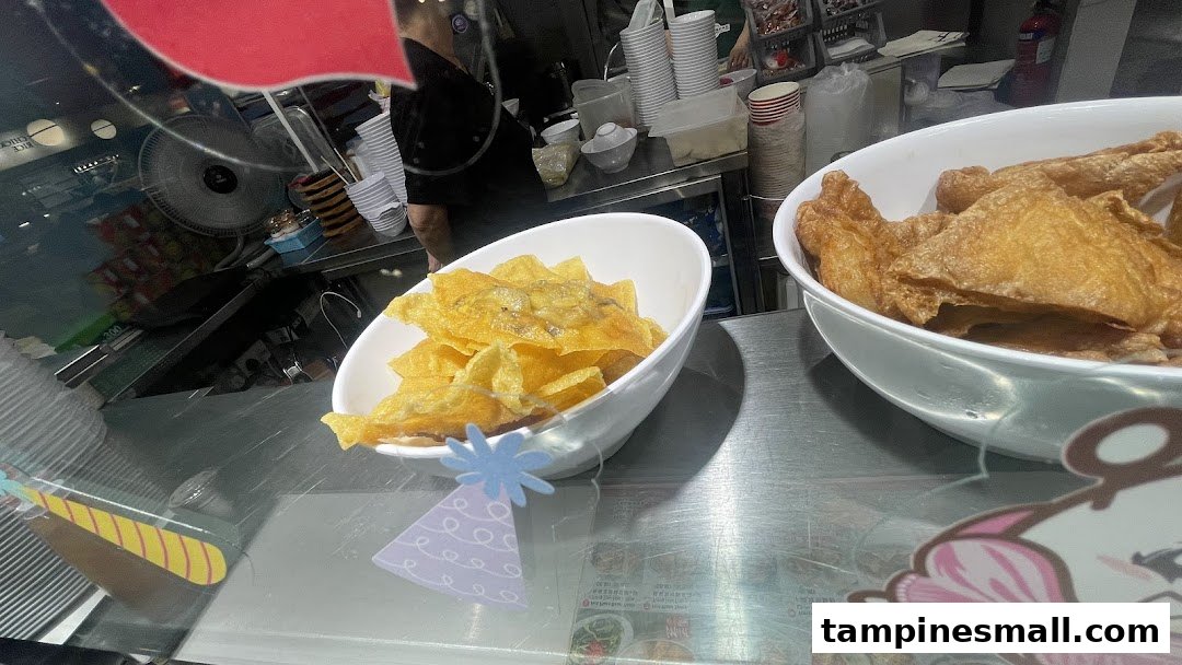 Bowls of crispy fried wontons and beancurd skin displayed at a food stall.