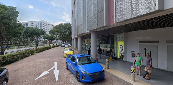 Exterior view of Tampines Mall entrance area with street, cars, and pedestrians.