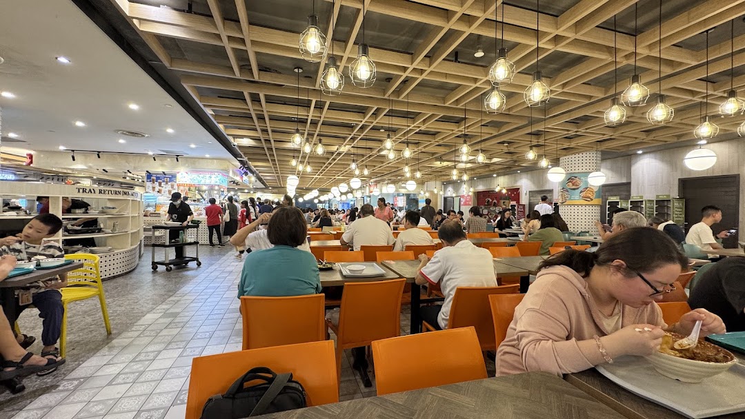 A bustling Kopitiam food court filled with patrons enjoying meals at various tables under warm lighting.