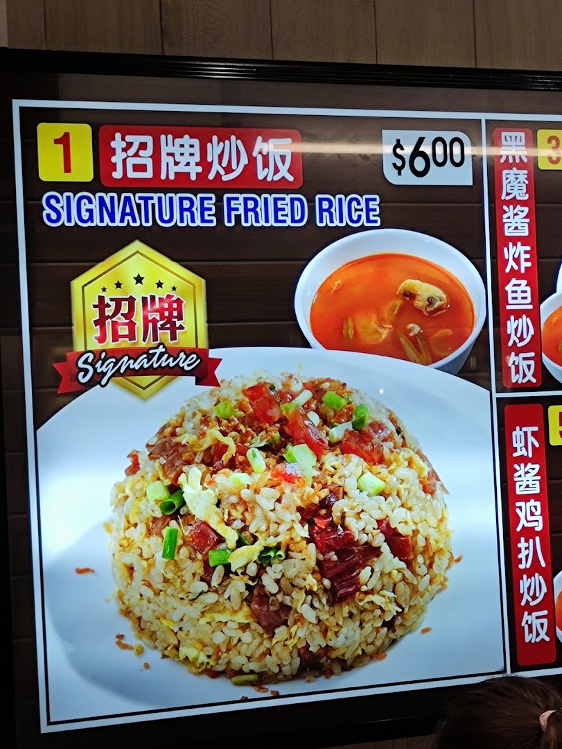 A digital menu board displaying Kopitiam's Signature Fried Rice with its price and an accompanying soup.