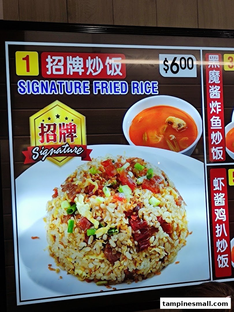 A digital menu board displaying Kopitiam's Signature Fried Rice with its price and an accompanying soup.