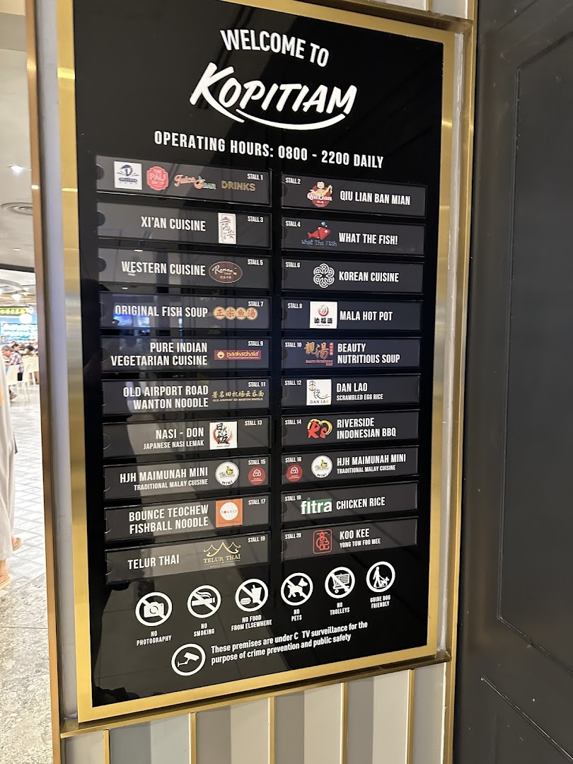 A large directory board at Kopitiam food court displaying operating hours and a diverse list of food stalls.