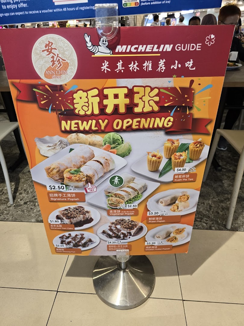 A standee displaying the menu and promotional items for Ann Chin, a Michelin Guide-recommended food stall.