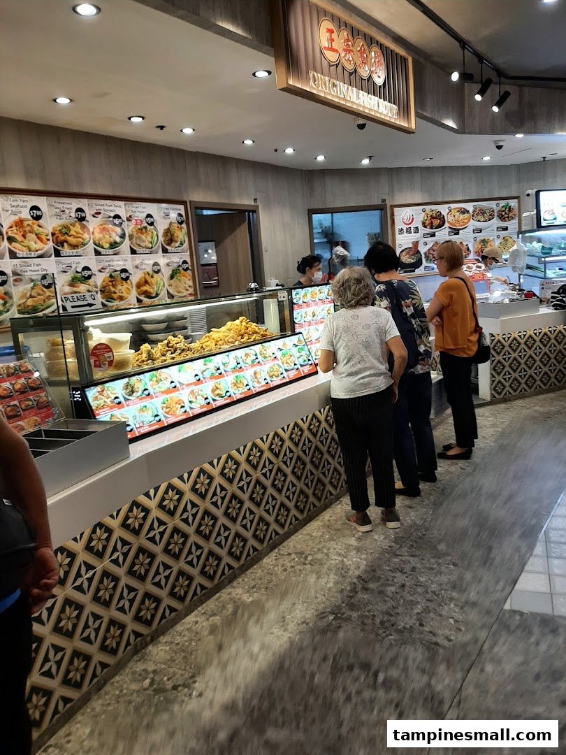 Customers queueing at Kopitiam's food counter with a variety of traditional dishes on display.