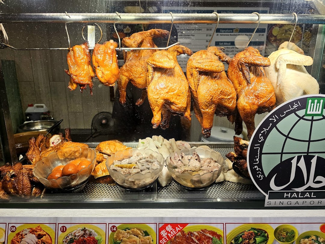 A vibrant display of roasted and steamed chickens, along with side dishes, in a Halal-certified food stall.