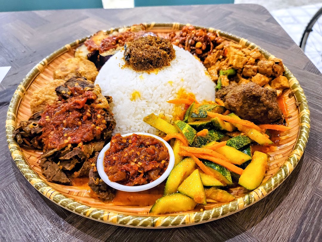 A vibrant platter of traditional Indonesian/Malay dishes with rice, vegetables, and various meats.