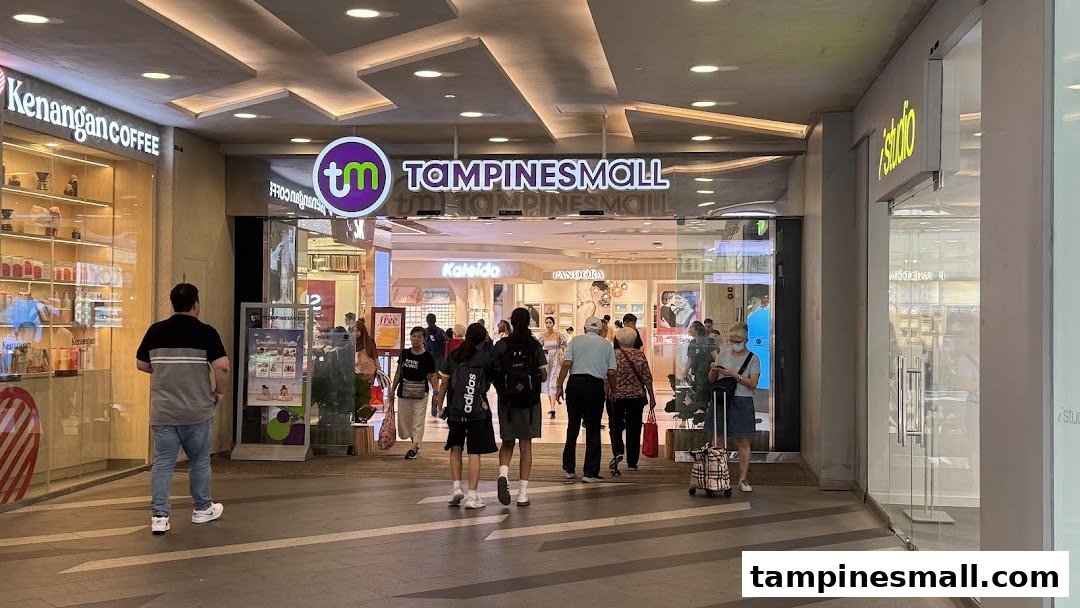 People walk through the brightly lit entrance of Tampines Mall, featuring various retail outlets.