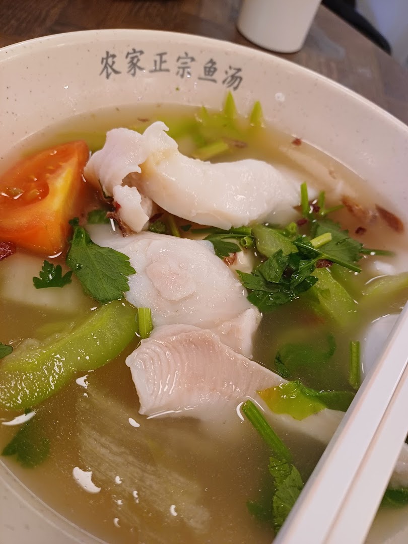 A close-up of a delicious bowl of fish soup with fresh fish slices, vegetables, and tomatoes.