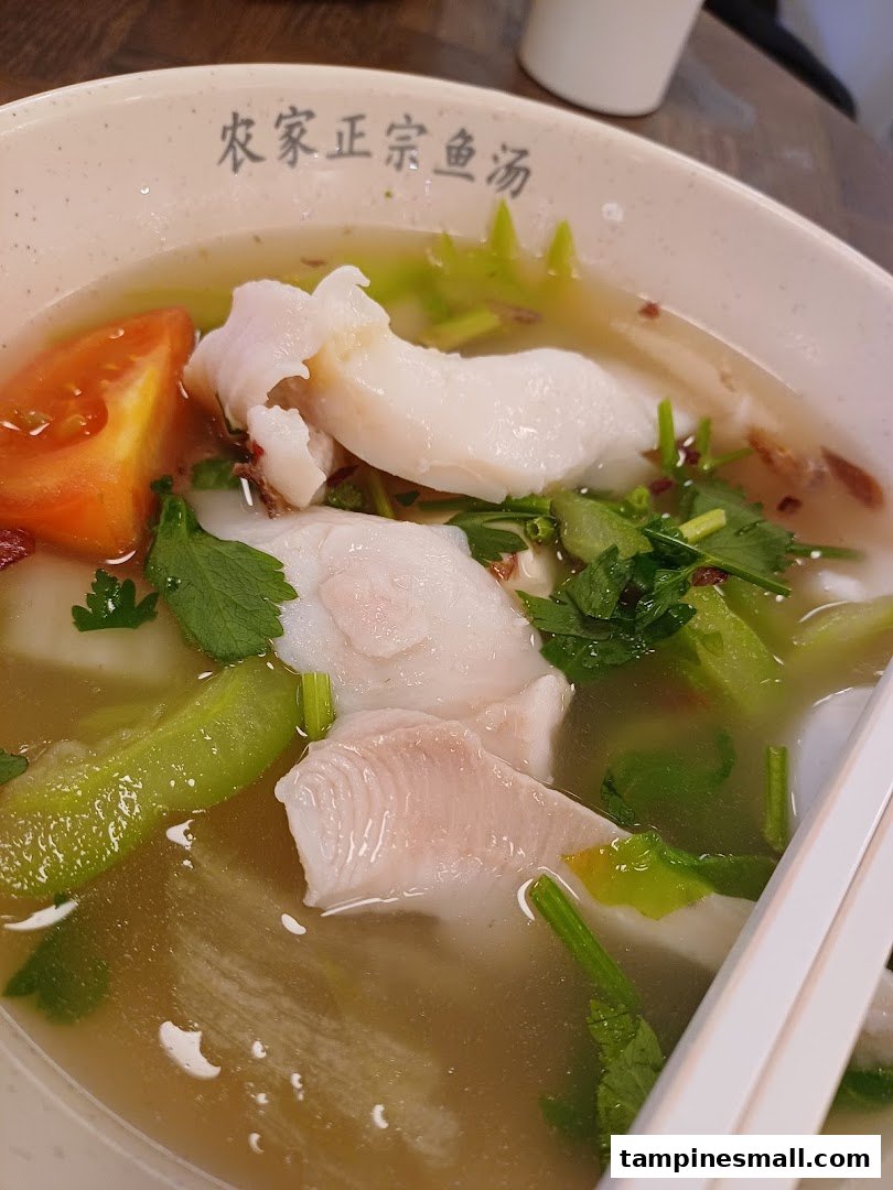 A close-up of a delicious bowl of fish soup with fresh fish slices, vegetables, and tomatoes.