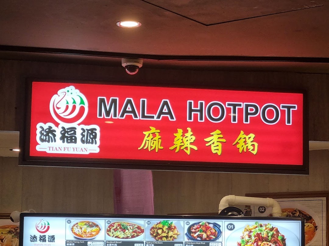 A bright red sign for Tian Fu Yuan Mala Hotpot above a display of various hotpot dishes and prices.