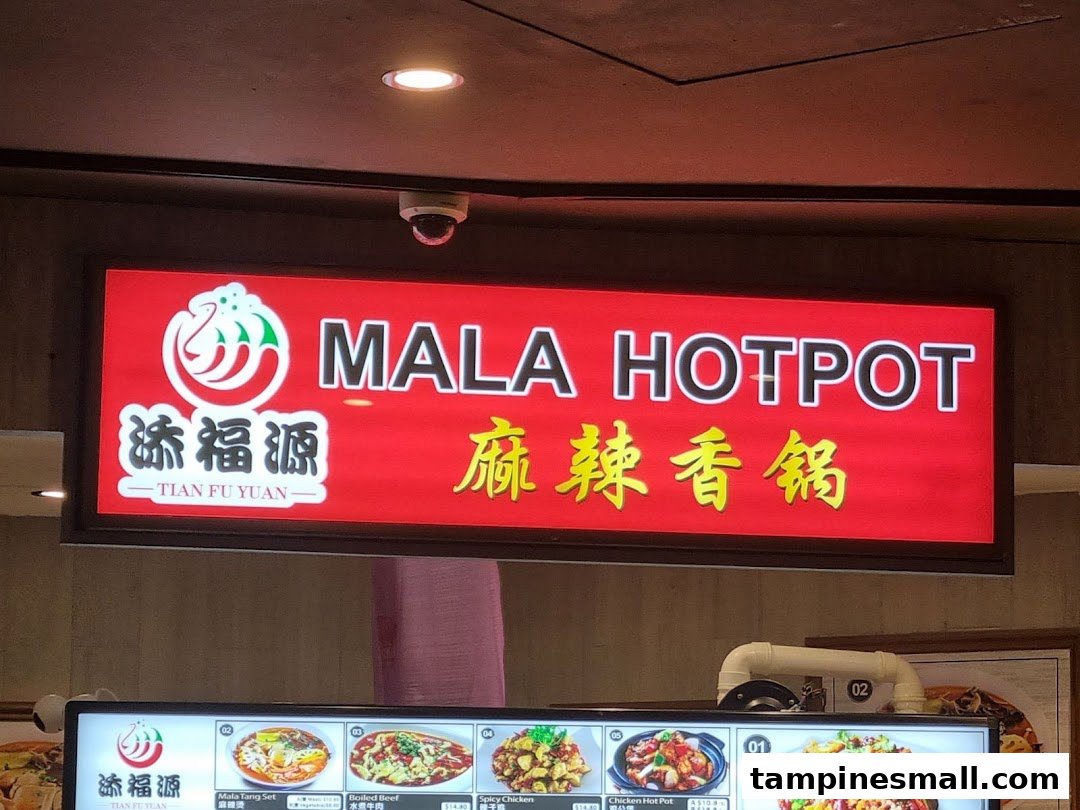 A bright red sign for Tian Fu Yuan Mala Hotpot above a display of various hotpot dishes and prices.