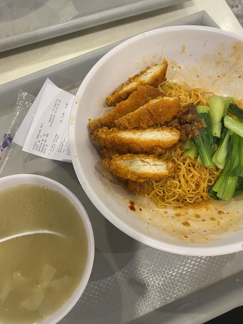 A delicious bowl of noodles topped with crispy fried chicken and bok choy, served with a side of soup.
