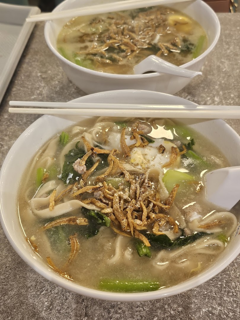 Two bowls of comforting noodles topped with crispy anchovies, vegetables, and egg, ready to be enjoyed.