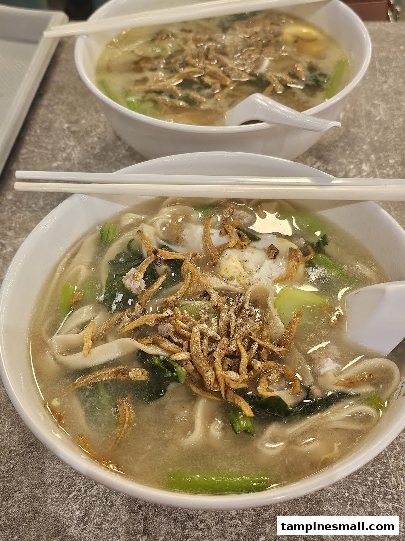 Two bowls of comforting noodles topped with crispy anchovies, vegetables, and egg, ready to be enjoyed.