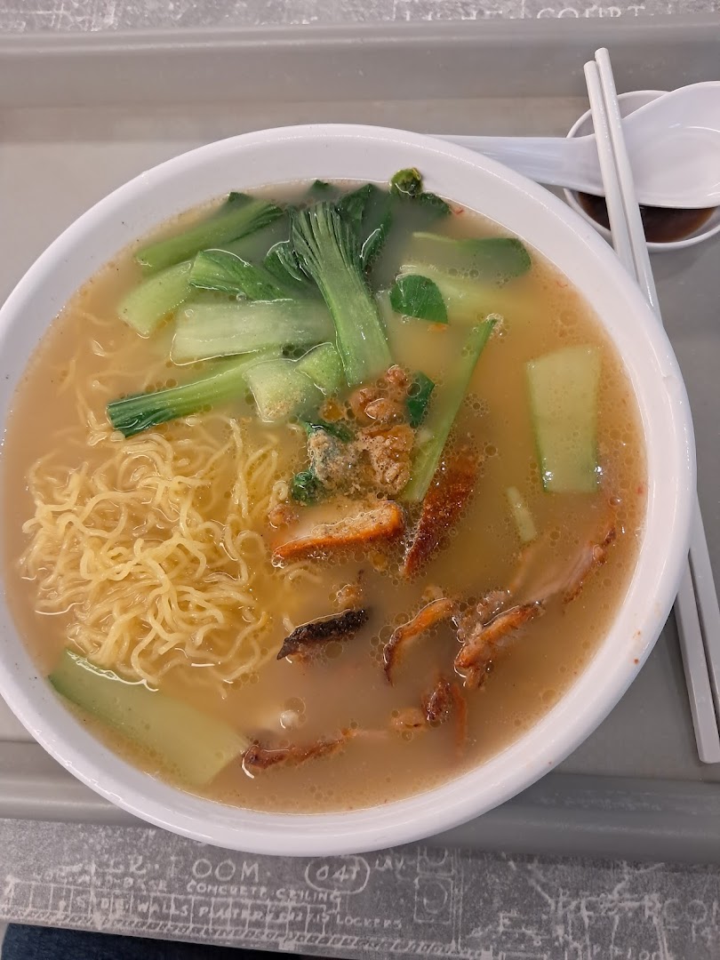 A close-up of a delicious bowl of noodles with char siew, vegetables, and a rich broth.