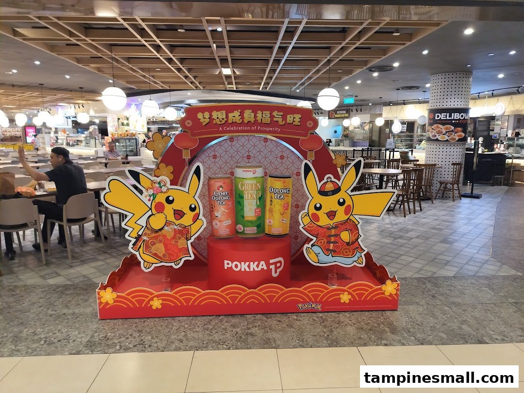 A large promotional display featuring Pikachu and Pokka drinks in a bustling food court setting.