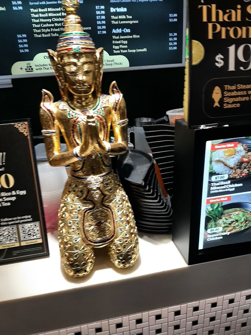 A golden Thai statue adorns a counter, with digital screens displaying menu items and promotions.