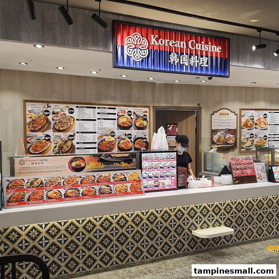 A bustling Korean cuisine food stall counter with a staff member and various menu displays.