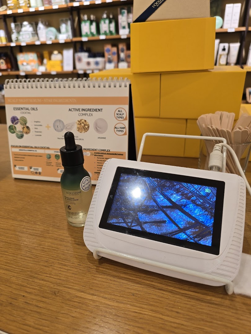 A L'Occitane display featuring a scalp analysis device, product, and information about scalp night serum.