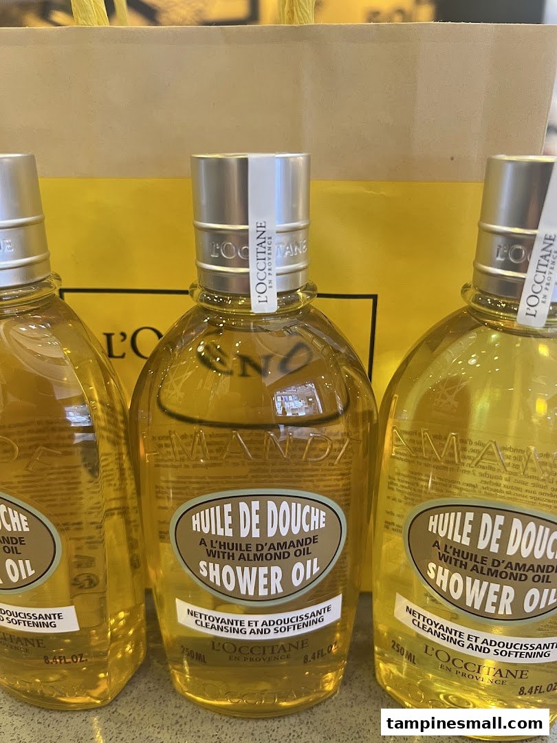 Three bottles of L'Occitane Almond Shower Oil are displayed, ready for purchase.