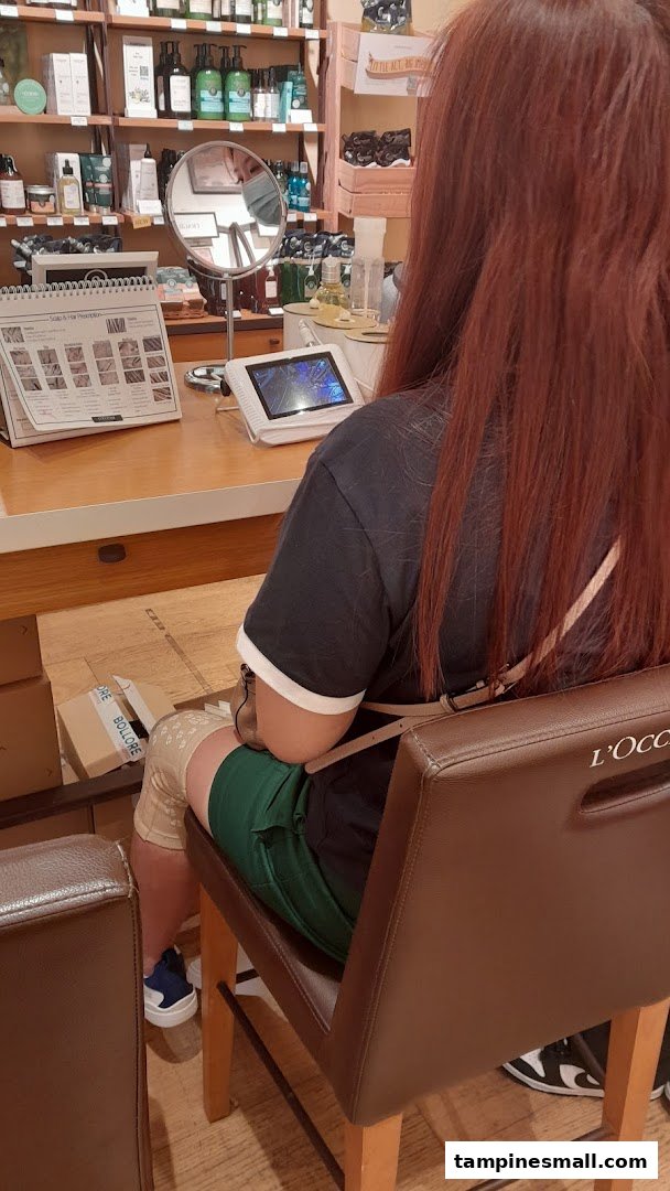 A customer receives a consultation at a counter inside the L'Occitane shop, surrounded by beauty products.