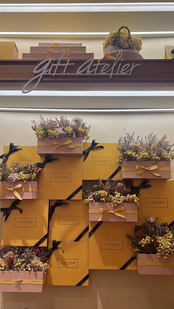 A vibrant display of L'Occitane gift boxes adorned with dried flowers, featuring a 'Gift Atelier' sign.