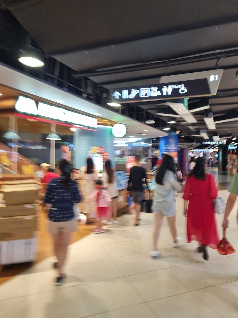 A bustling mall interior with shoppers walking past a health and nutrition store.