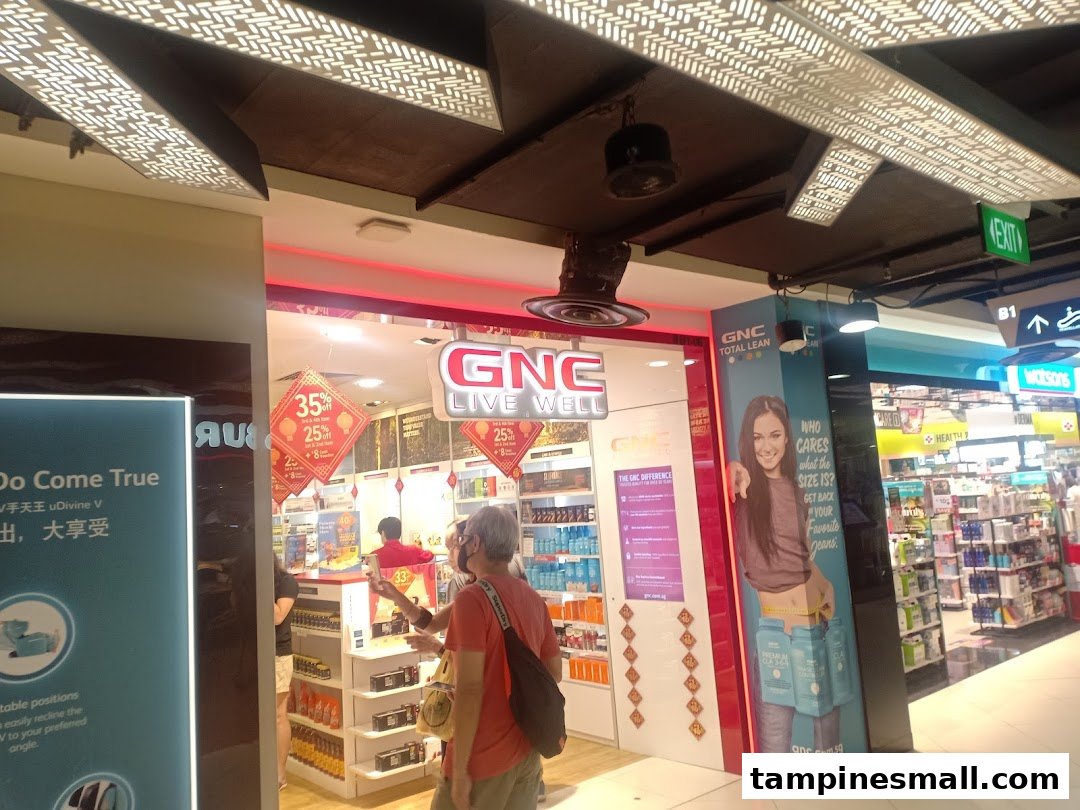 Brightly lit GNC store entrance showcasing health products, promotional offers, and customers browsing.