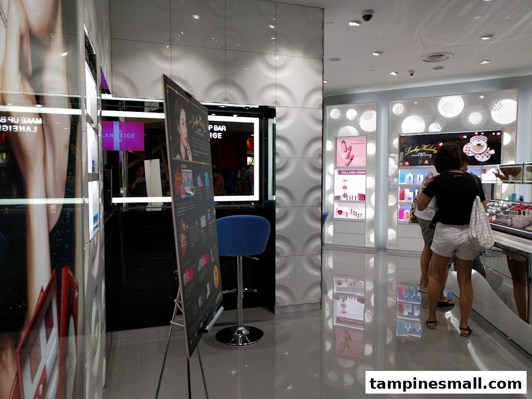 Interior view of a Laneige beauty store featuring product displays, a makeup bar, and customers browsing.