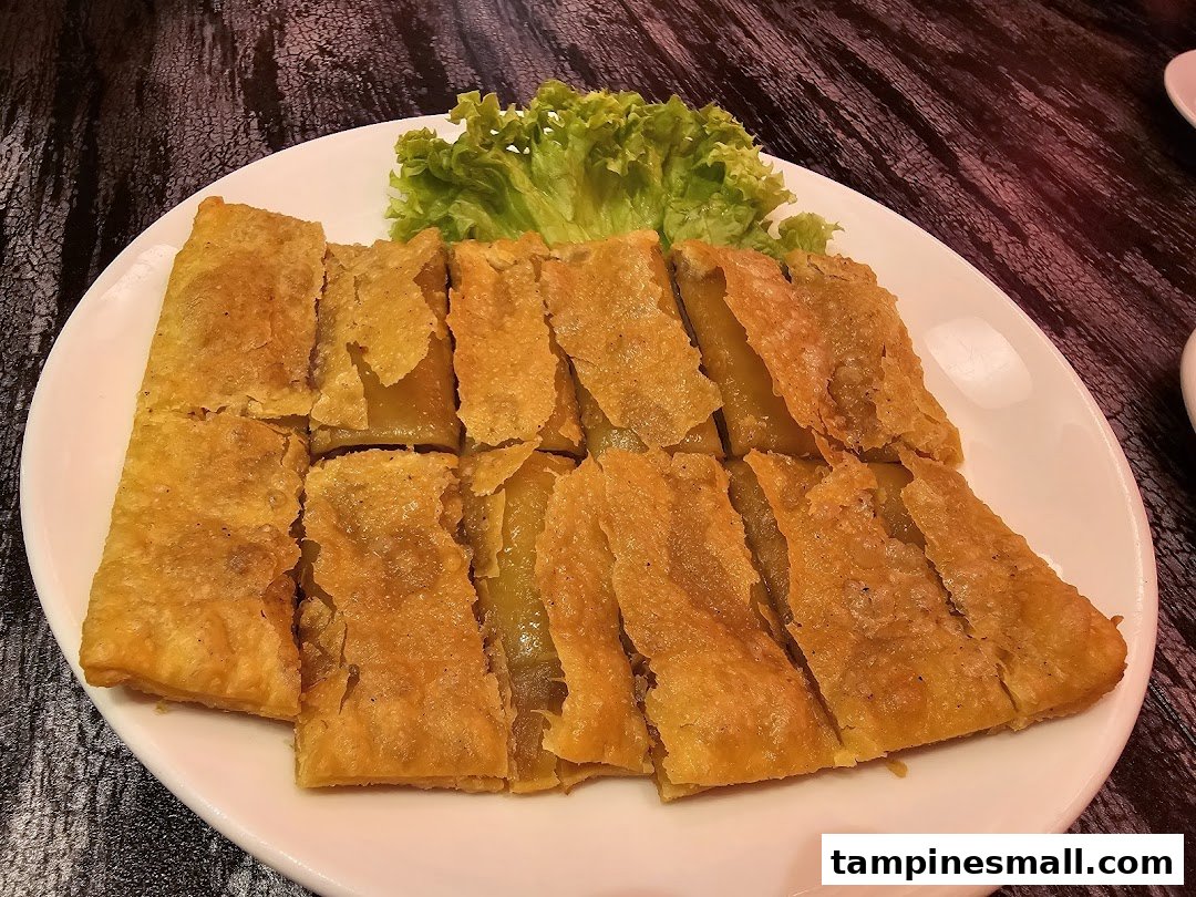 A plate of golden-fried pastry or pancake slices with a side of fresh lettuce.
