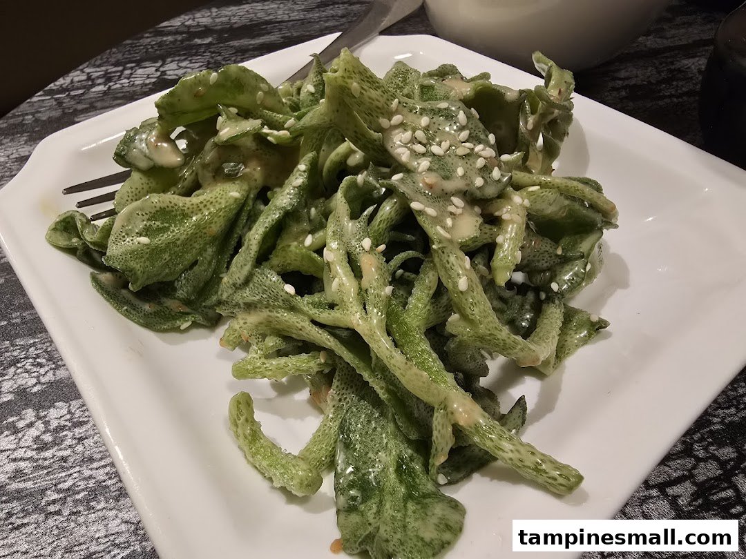A plate of green leafy vegetables with a creamy sauce and sesame seeds.