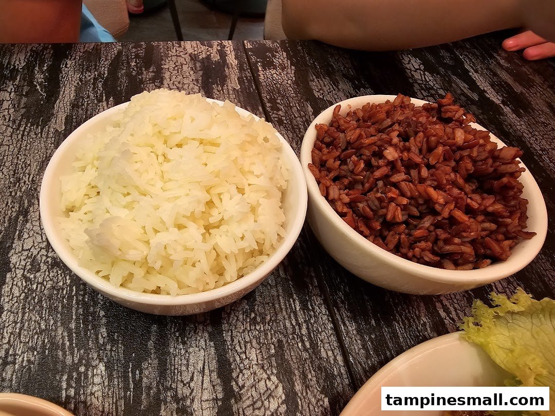 Two bowls of rice, white and red, served on a dark wooden table.
