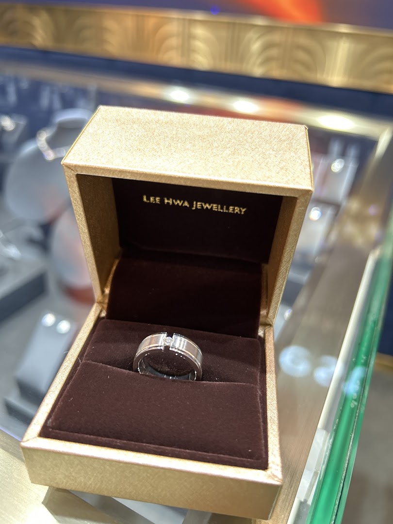 A silver ring with a single diamond set in a Lee Hwa Jewellery branded box.